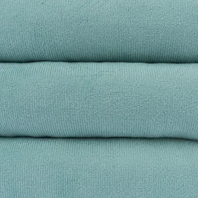 Close-up van turquoise stof met fijne breistructuur, geschikt voor huisdierproducten of accessoires.