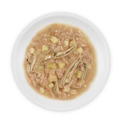 Primo piano di cibo umido con pezzi di pesce e dadini di patate in una ciotola bianca.