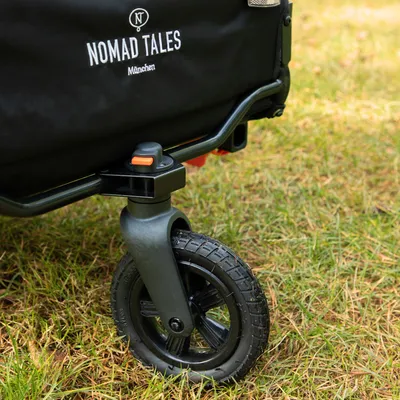Nomad Tales München-tryck på svart tyg, detaljvy av ett stabilt hjul med plastram och orange låsmekanism.