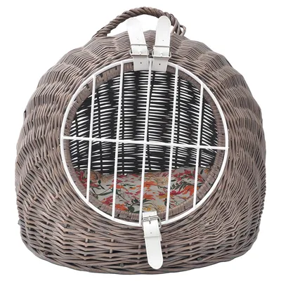 Pyöreä punottu kori, jossa valkoinen metallinen eturitilä ja kaksi solkikiinnitystä, sisällä kukkakuvioinen pehmuste. Kantokahva ylhäällä.