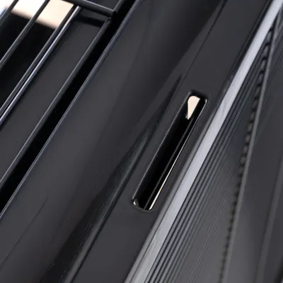 Close-up of a black plastic handle with ventilation slots, part of a transport box or cage.
