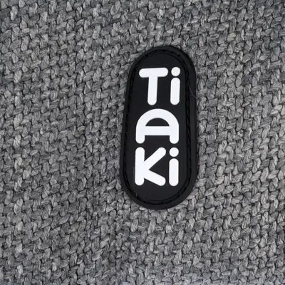 Tiaki-Logo auf grauem, gewebtem Stoff.