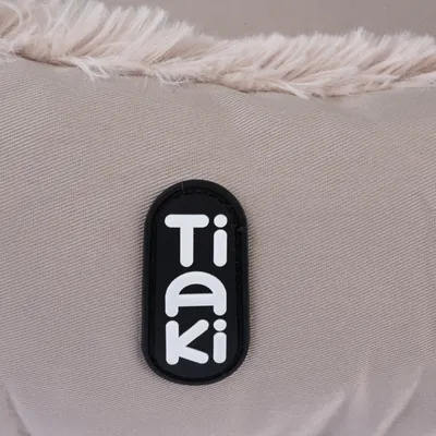 Tiaki logo on beige fabric with faux fur trim.