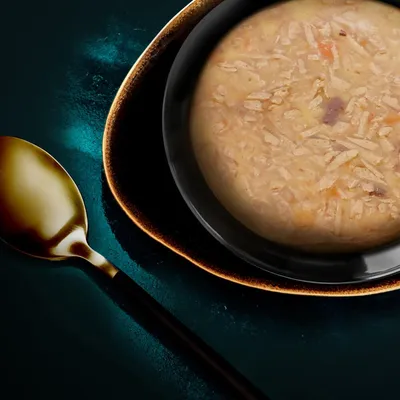 Povečava sklede z vlažnimi, sesekljanimi sestavinami, postreženimi na temnem krožniku. Zlata žlica poleg.