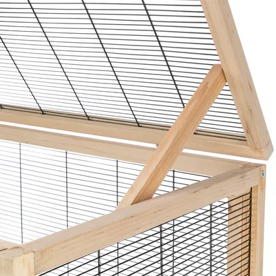 Recinto con telaio in legno e pareti a griglia metallica, tetto triangolare con travi di supporto.