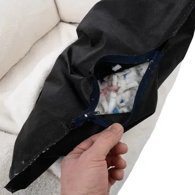 Close-up of a black cover with zip showing filling made of colourful foam pieces. Hand opening the cover.