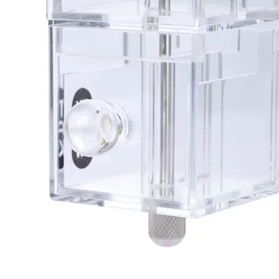 Gros plan sur un tiroir transparent avec poignée ronde en plastique et éléments métalliques visibles, structure en plastique transparent.