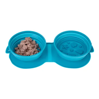 Gamelle double pliable en silicone bleu, une coupelle avec pâtée, l’autre vide avec motifs en relief au fond. Convient pour nourriture et eau d’animaux.