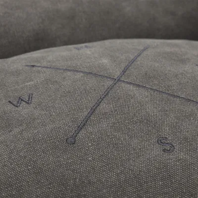 Grauer Stoff mit gesticktem Kompassmotiv, Buchstaben N, S, W und E sichtbar.