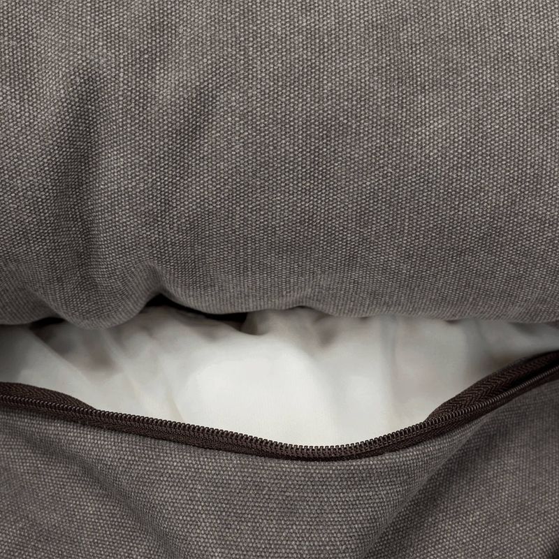 Nahaufnahme eines grauen Stoffbezugs mit Reißverschluss, darunter sichtbare weiße Füllung. Zeigt Details des Materials und der abnehmbaren Hülle.