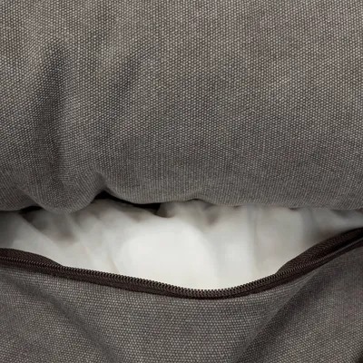 Nahaufnahme eines grauen Stoffbezugs mit Reißverschluss, darunter sichtbare weiße Füllung. Zeigt Details des Materials und der abnehmbaren Hülle.