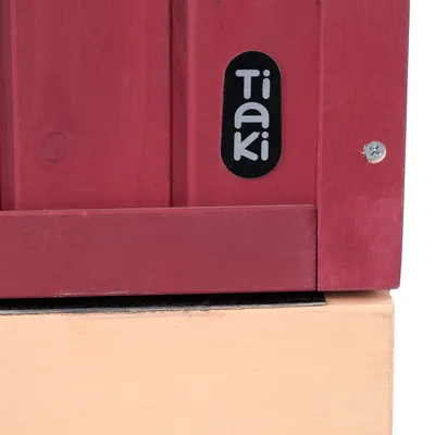 Tiaki-Logo auf rotem Holzmaterial, befestigt mit einer silbernen Schraube.