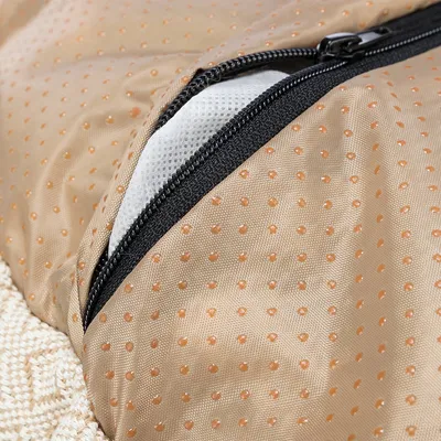 Nahaufnahme eines beige gepunkteten Stoffes mit schwarzem Reißverschluss und weißem Netzmaterial darunter.