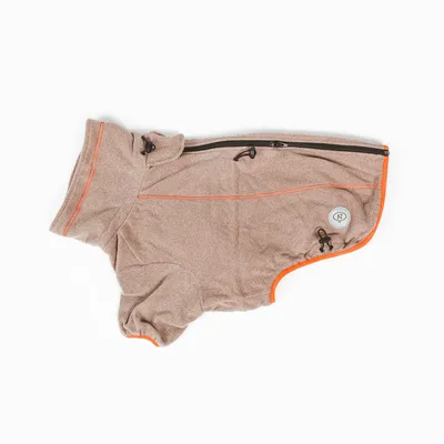Manteau pour chien en tissu beige avec fermeture éclair noire, cordons de serrage et bordure orange, écusson rond marqué 'NT' visible sur le côté.