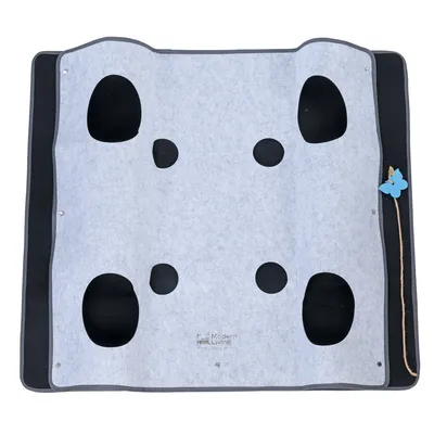 Tapis d’activité Modern Living en feutre gris avec huit ouvertures de tailles variées et un jouet papillon bleu attaché à une ficelle sur le côté droit. Marque visible : Modern Living.
