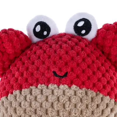 Rood pluchen speelgoed in de vorm van een krabbenkop met geborduurde ogen en mond, beige onderzijde. Gestructureerd oppervlak van zachte stof.