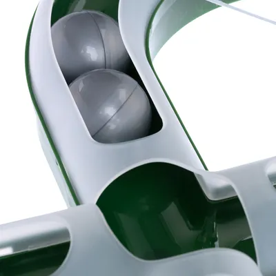 Vista detallada de un juguete verde y blanco con dos bolas grises en un soporte, adecuado para juego interactivo.