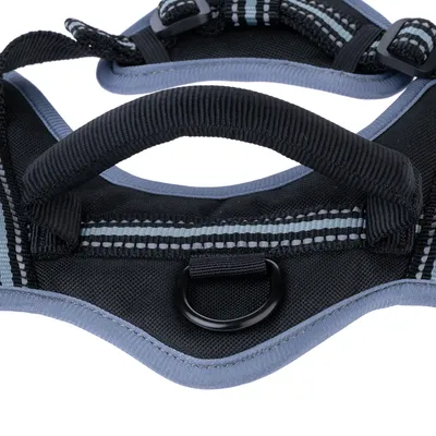 Nahaufnahme eines schwarzen Hundegeschirrs mit gepolstertem Griff, reflektierenden Streifen und Metallring zur Befestigung einer Leine.