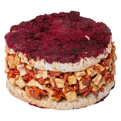 Snack per pet a base di gallette di riso pressato, pezzi di verdura rossa e bianca essiccati, con uno strato di polvere rossa sopra.