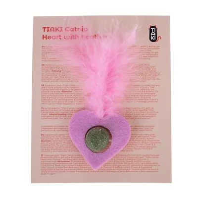 Jouet pour chat TIAKI Catnip Heart with Feather, cœur en feutre rose avec plume et pastille verte, sur carte d’instructions multilingue. Marque TIAKI visible en haut à droite.