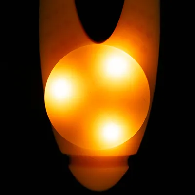 Lysande leksak med tre orange ljuspunkter, lämplig för mörka miljöer.