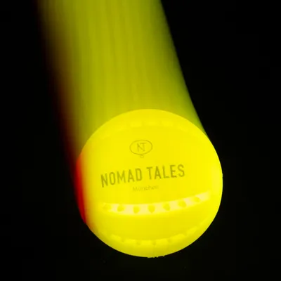 Nomad Tales München. Lysende gult produkt med synligt logo og tekst.