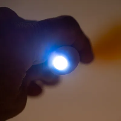 Hånd holder en lille lommelygte med klart LED-lys, egnet til præcis belysning.