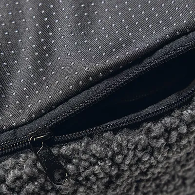 Gros plan sur une housse en tissu gris avec fermeture éclair et surface antidérapante à picots visibles.