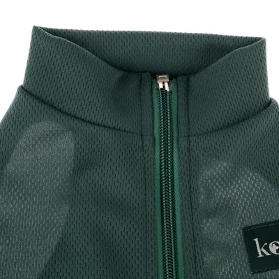 Nahaufnahme eines dunkelgrünen Stoffes mit Reissverschluss und Logo-Ausschnitt 'kee'.