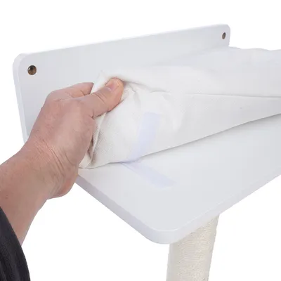 Una mano mostra come un rivestimento in tessuto bianco con chiusura a strappo viene fissato su una piattaforma bianca.