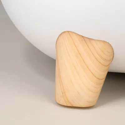 Wooden leg of a white piece of furniture, smoothly sanded with visible grain.