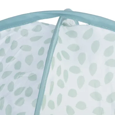 Détail d’un tissu blanc à motif feuilles vert clair avec bordure en tissu bleu clair, structure visible en plastique ou métal sous le tissu.