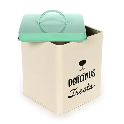 Beżowe metalowe pudełko z zieloną pokrywką i czarnym napisem 'Delicious Treats', odpowiednie do przechowywania smakołyków dla zwierząt.