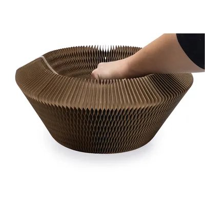 Hand greift in ein braunes, wabenförmiges Produkt aus Papiermaterial. Demonstration der Flexibilität und Form des Produkts.