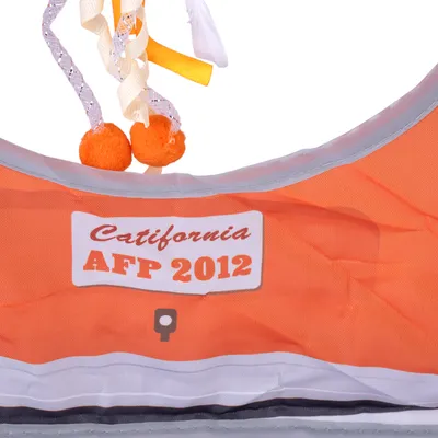 Orangefarbene Spielzeugtasche mit Schriftzug 'Catifornia AFP 2012' und hängenden Bändern mit orangefarbenen Kugeln.