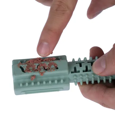 Demonstration: filling soft food into the openings of a green toy with knobs and grooves.