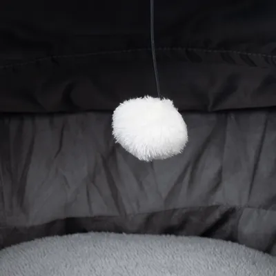 White plush ball on a black string, part of a toy or accessory for pets.