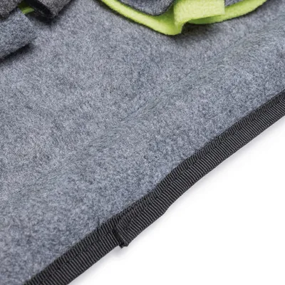 Detailaufnahme einer grauen Filzoberfläche mit schwarzem Rand und grünen Stoffelementen.