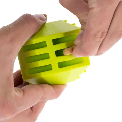 Una mano mostra come inserire snack in un gioco verde con fessure.