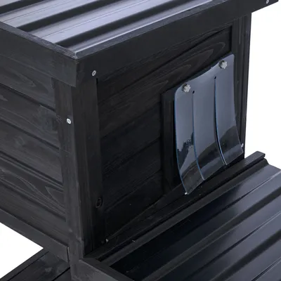 Schwarzes Holzhaus mit transparenten Kunststoff-Lamellen als Eingang und geriffeltem Dach aus Metall.