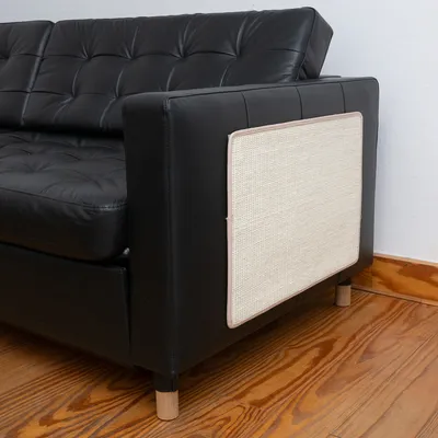 Kratzschutz aus beigem Sisal-Material, befestigt an der Seite eines schwarzen Ledersofas. Schutz für Möbel vor Kratzspuren.