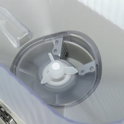 Close-up view of a transparent container with rotating plastic blades and metal parts, presumably part of a feeder or mixing system.