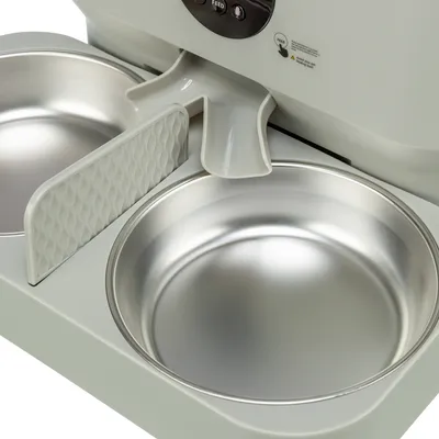 Automatic feeder with two stainless steel bowls and divider. Control panel with visible feed button.