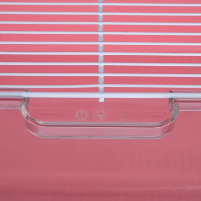 Detailansicht eines weißen Metallgitters mit transparenter Kunststoffkante und Recycling-Symbolen auf rosa Hintergrund.