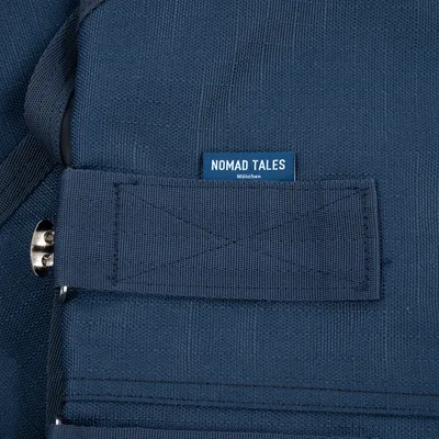 Nomad Tales München. Detailansicht eines blauen Stoffmaterials mit Metallverschluss.