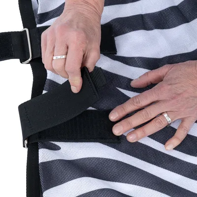 Primo piano di mani che fissano una chiusura in velcro nera su un tessuto a righe.