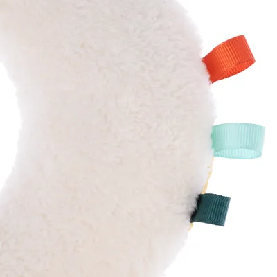 Soft, white plush material with coloured loops in orange, turquoise and dark green. Close-up of a toy or accessory.