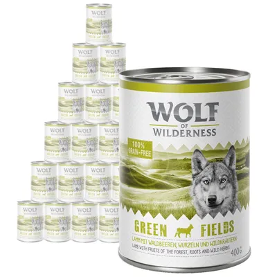 Wolf of Wilderness Green Fields 400g tins, visible text: 100% grain-free, lamb with fruits of the forest, roots and wild herbs. Multiple tins shown in a pyramid stack.