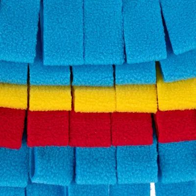 Primo piano di strisce in pile colorate blu, gialle e rosse, forse parte di un gioco o di una coperta per animali.