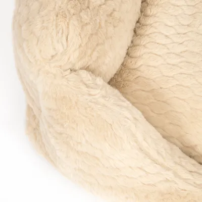 Detailný záber na béžový, nadýchaný materiál so štruktúrovaným povrchom, pravdepodobne časť pelechu alebo deky pre domáce zvieratá.